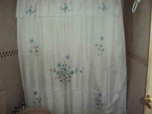 een badkamer met een douchegordijn met blauwe bloemen erop bij Cabañas Wayramuyu in Merlo
