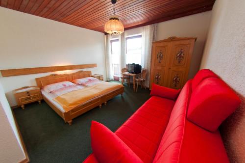 1 dormitorio con 1 cama y 1 sofá rojo en Gasthof Koglerhof en Ternberg