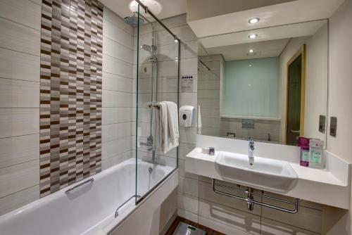 a bathroom with a sink and a tub and a mirror at Premier Inn Dubai Ibn Battuta Mall in Dubai