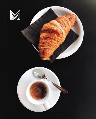 a plate with a croissant and a cup of coffee at Gladius Hotel & Suites-Parramatta Marsden Street in Sydney