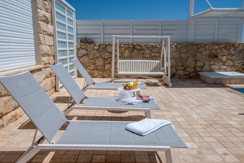 a patio with two chairs and a table and a swing at Nofesh Ba Alon 10 in Rosh Pinna