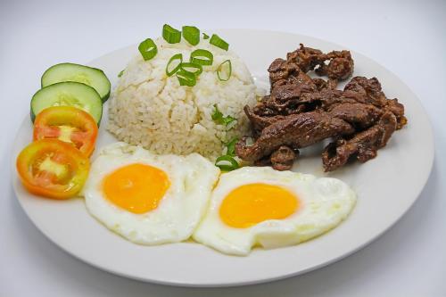 a plate of food with eggs and meat and rice at World View Pension House in Dumaguete