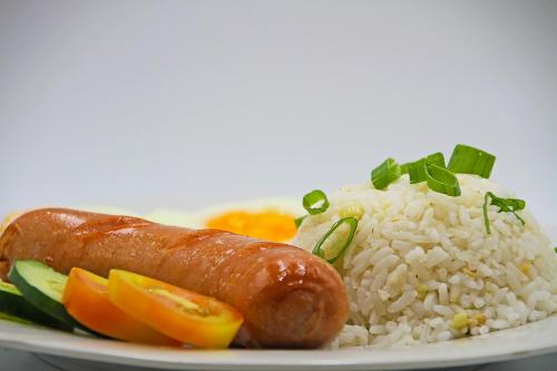 a plate of rice and a sausage and vegetables at World View Pension House in Dumaguete