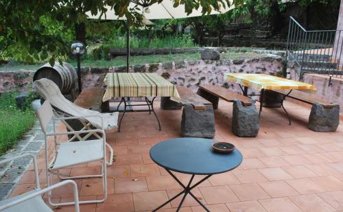 a patio with tables and chairs and a table and benches at Case Zuccaro in Trecastagni