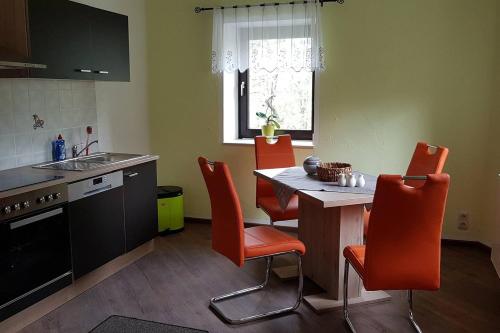 cocina con sillas de color naranja y mesa de cocina en Waldhufenidyll Königswalde im Erzgebirge, en Königswalde