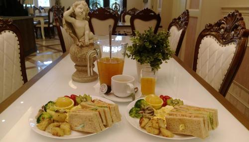 a table with two plates of food and two glasses of orange juice at Buckingham Palace B&B in Beipu