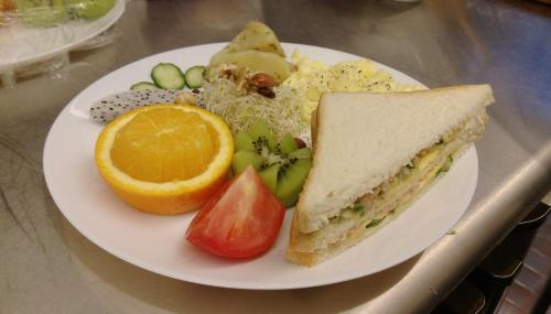 a white plate of food with a sandwich and fruit at Buckingham Palace B&B in Beipu