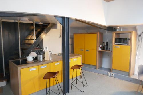a kitchen with yellow cabinets and two stools at Boathotel Rotterdam Wilhelmina in Rotterdam