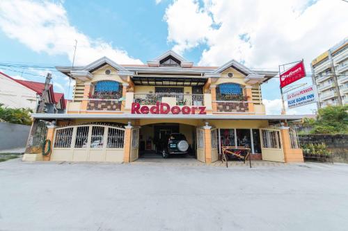 un edificio con un cartello di bordo rosso sulla parte anteriore di RedDoorz at La Casa Guesthouse former RedDoorz at Tamarind Street Angeles City a Angeles