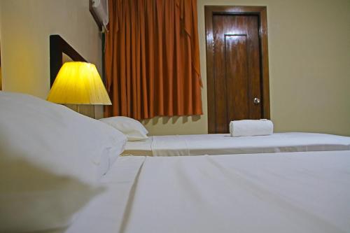 a bedroom with two beds with a lamp and a mirror at World View Pension House in Dumaguete