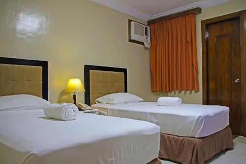 a hotel room with two beds and a window at World View Pension House in Dumaguete