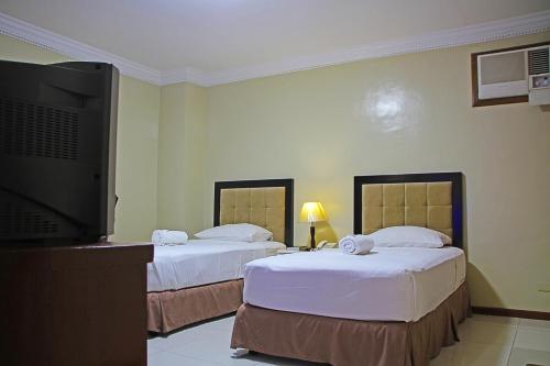 a hotel room with two beds and a flat screen tv at World View Pension House in Dumaguete