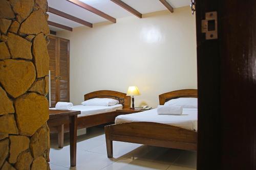 a bedroom with two beds and a stone wall at World View Pension House in Dumaguete