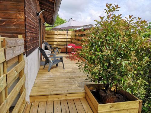 a wooden deck with a potted plant and an umbrella at Hossegor Les Bécasses in Soorts-Hossegor