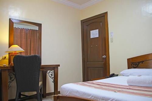 a bedroom with a bed and a desk and a chair at World View Pension House in Dumaguete
