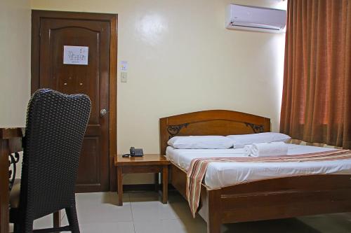 a bedroom with a bed and a table and a chair at World View Pension House in Dumaguete