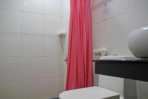 a bathroom with a red shower curtain and a toilet at World View Pension House in Dumaguete