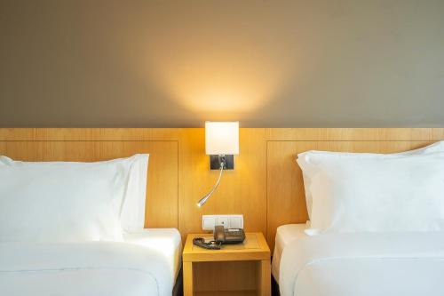 a hotel room with two beds and a lamp at HF Tuela Porto in Porto