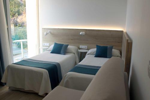 two beds in a room with a window at Rocatel in Canet de Mar
