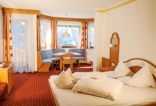 ein Hotelzimmer mit 2 Betten und einem Tisch in der Unterkunft Hotel Garni Romantica in Jerzens