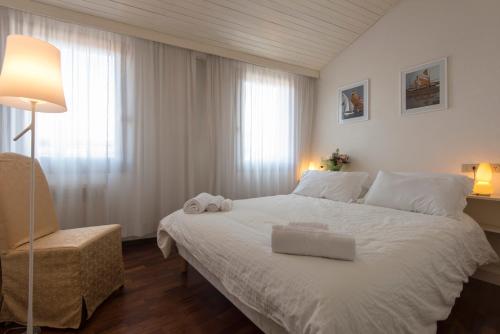 una camera con letto bianco, lampada e sedia di Ca'Baloni a Venezia