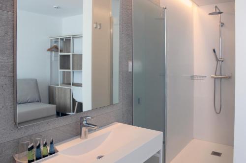 uma casa de banho com um lavatório e um chuveiro com um espelho. em Rocatel em Canet de Mar