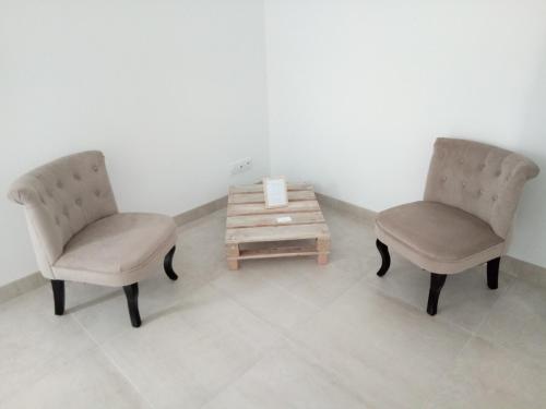 - deux chaises et une table basse dans une chambre dans l'établissement La Closerie de Sens, à Sens-de-Bretagne