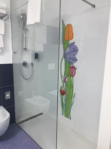a shower with a glass door with flowers painted on it at Saracen Sands Hotel & Congress Centre - Palermo in Isola delle Femmine
