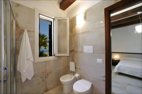 a bathroom with a toilet and a bed and a window at Villa Antonia - Vasca Idromassaggio Terrazza Vista Mare in San Vito lo Capo