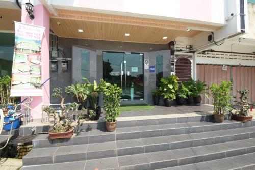a building with a bunch of potted plants on the stairs at 56 HOTEL in Mentekab