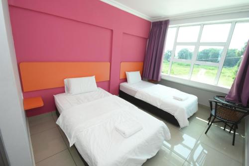 a room with two beds and a pink wall at 56 HOTEL in Mentekab