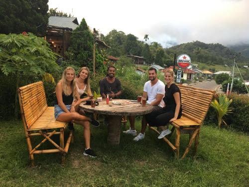 a group of people sitting around a wooden table at Mahoni Guest House in Kelimutu