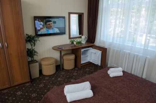 アドレルにあるグラナ ホテルのデスク、壁掛けテレビが備わる客室です。