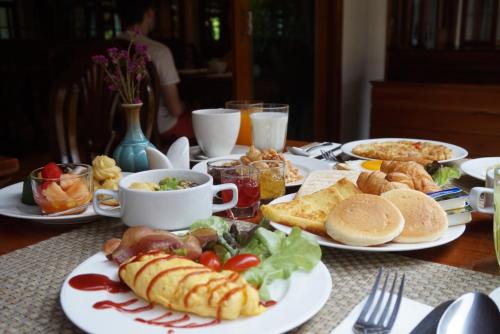 a table with plates of breakfast food on it at Pingviman Hotel in Chiang Mai