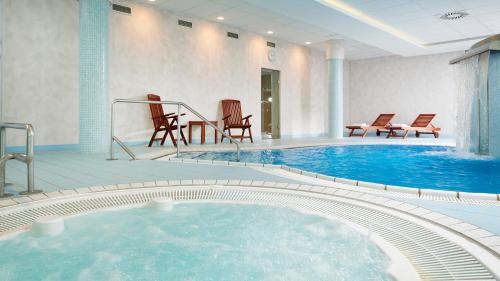 a large swimming pool with chairs in a hotel room at OREA Spa Hotel Cristal in Mariánské Lázně