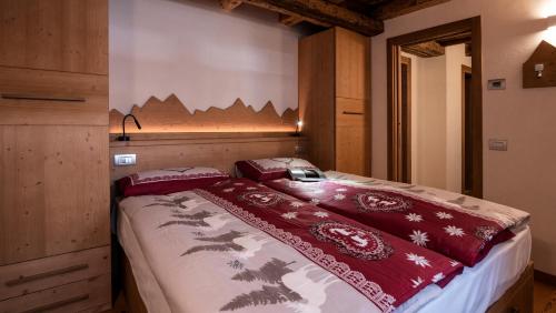 a bedroom with a bed with red comforter at Chalet Stella Alpina in Val di Zoldo