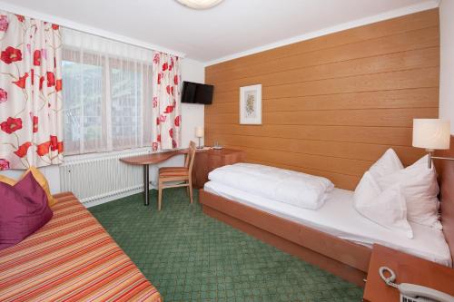 レッヒにあるHotel - Pension Fortunaのベッド2台とテーブルが備わるホテルルームです。