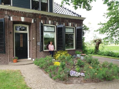 a woman standing in the window of a brick house at de Wylgepleats in Jutrijp