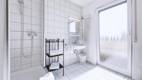 La salle de bains blanche est pourvue d'une douche et d'un lavabo. dans l'établissement Hotel Restaurant Austüble, à Elchingen