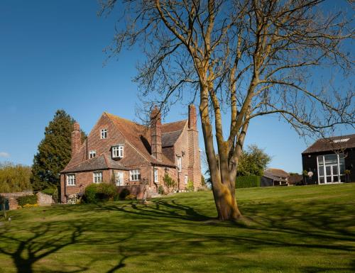 ein großes Backsteinhaus mit einem Baum im Hof in der Unterkunft Goss Hall Bed & Breakfast in Sandwich