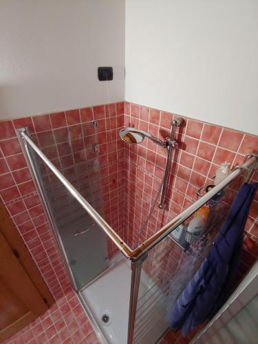 een glazen douche in een badkamer met rode tegels bij Casa Dolce Casa in Valdobbiadene