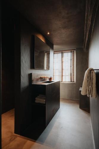 a black bathroom with a sink and a window at Amitié in Kinrooi