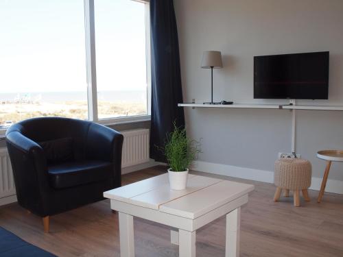 a living room with a chair and a table and a tv at Residence Le Mistral in Noordwijk aan Zee