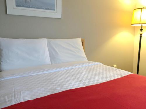 a bedroom with a bed with a white and red blanket at Auberge du Grand Lac in Magog-Orford
