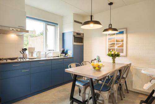 a kitchen with blue cabinets and a wooden table at Center Parcs Zandvoort beach in Zandvoort