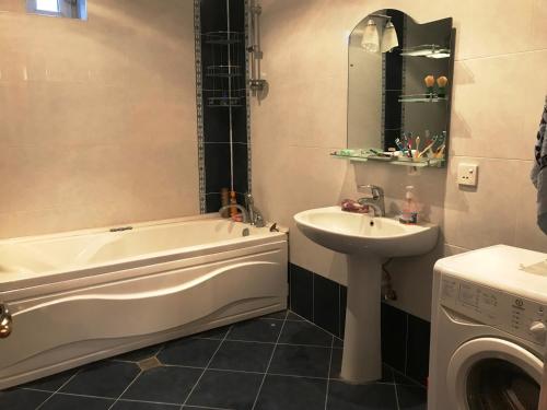 uma casa de banho com uma banheira, um lavatório e uma máquina de lavar roupa em My house in Buzovna em Baku