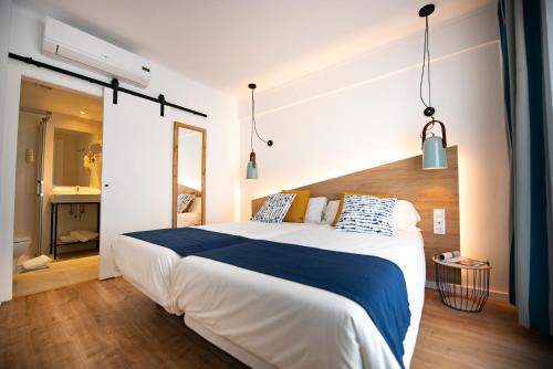 um quarto com uma grande cama branca com lençóis azuis em Hostal Blanca em Can Picafort