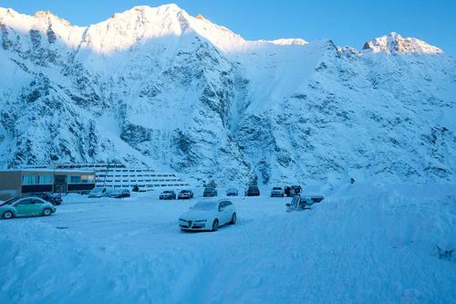 a group of cars parked in a parking lot with snow covered mountains at Appartement la Cabane d'Engaly in Aragnouet