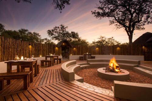 a patio with a fire pit with tables and chairs at Vuyani River Lodge in Hoedspruit