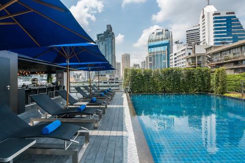 曼谷的住宿－The Key Premier Hotel Sukhumvit Bangkok，大楼内带躺椅和遮阳伞的游泳池